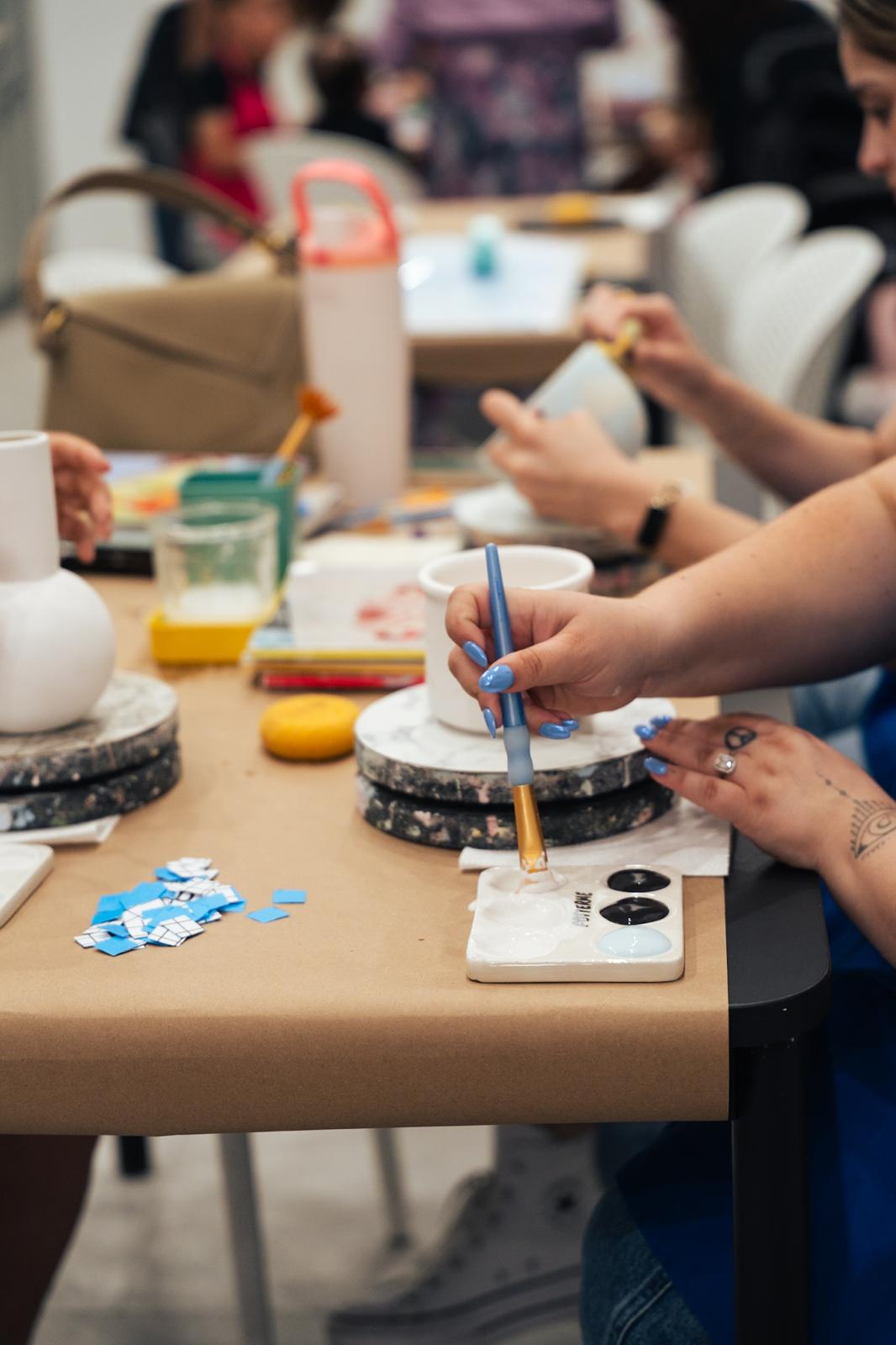 A group of guests painting pottery together around a PotterMe table